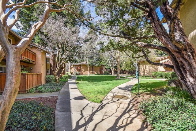 view of home's community with a lawn and fence