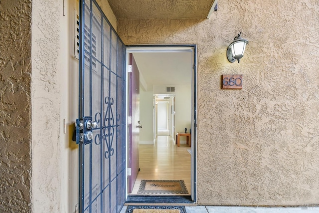 entrance to property featuring visible vents and stucco siding