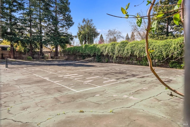 view of home's community with a tennis court and fence