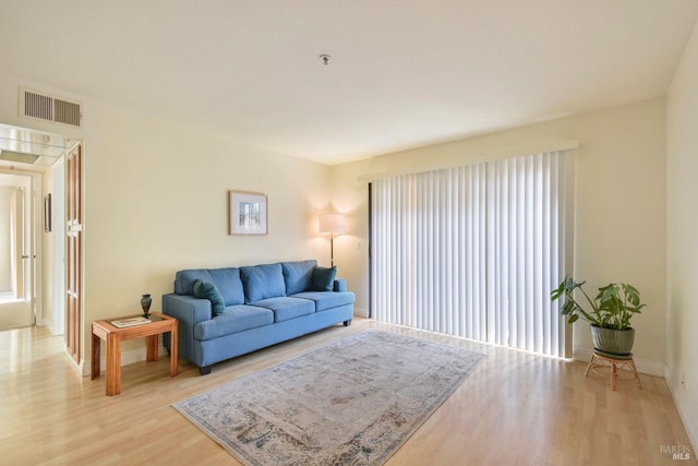 living room with visible vents, baseboards, and light wood-style flooring