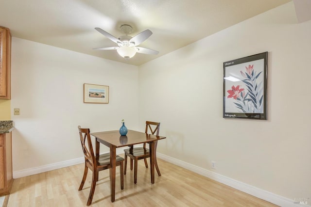 dining area with light wood-style flooring, a ceiling fan, and baseboards