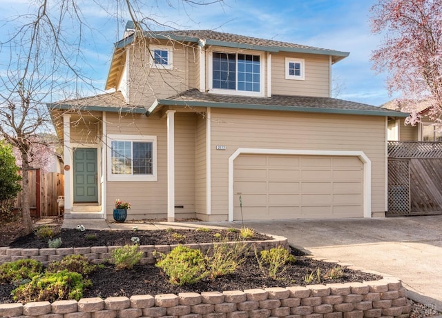 traditional home with roof with shingles, concrete driveway, an attached garage, and fence