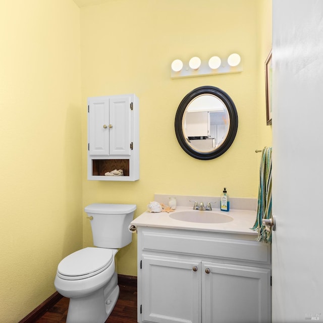 bathroom featuring baseboards, toilet, wood finished floors, and vanity