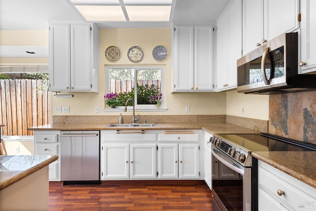 kitchen featuring dark wood finished floors, white cabinets, appliances with stainless steel finishes, and a sink