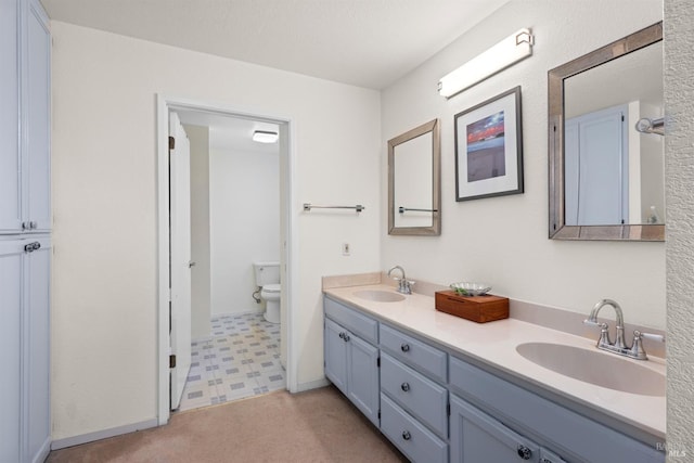 bathroom featuring double vanity, tile patterned floors, toilet, and a sink