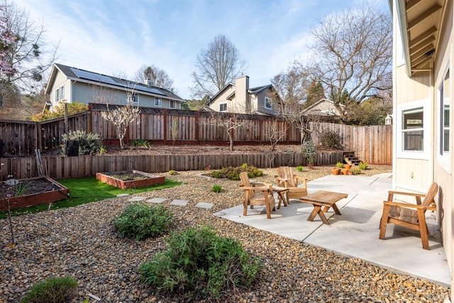 view of yard featuring a patio, a garden, and a fenced backyard