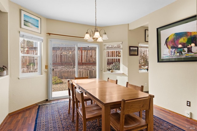 dining area with baseboards, an inviting chandelier, and wood finished floors