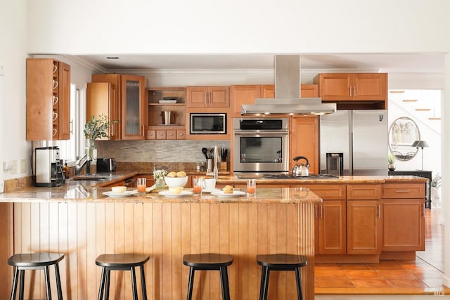 kitchen with a peninsula, a sink, extractor fan, glass insert cabinets, and appliances with stainless steel finishes