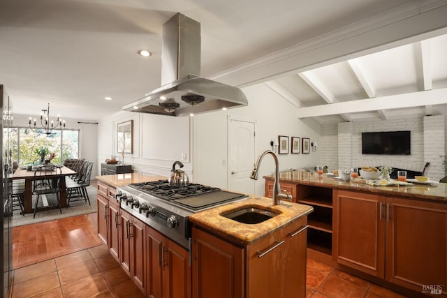 kitchen with stainless steel gas cooktop, island exhaust hood, a kitchen island with sink, and a sink