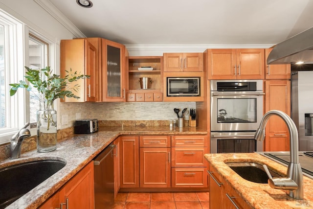 kitchen with light tile patterned flooring, appliances with stainless steel finishes, light stone countertops, and a sink