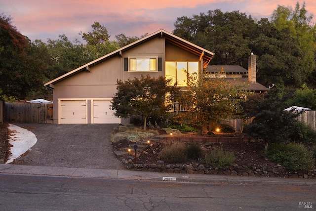 view of front of home with driveway, a garage, and fence