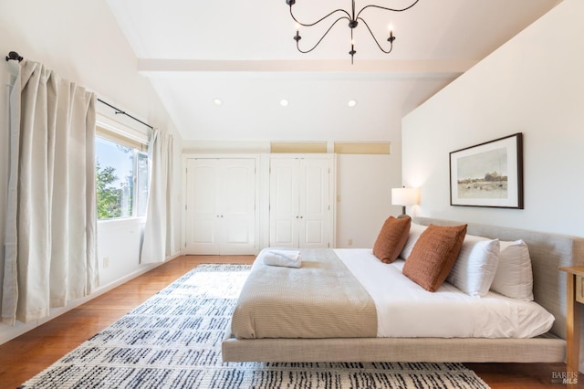 bedroom featuring two closets, recessed lighting, light wood finished floors, a chandelier, and vaulted ceiling with beams