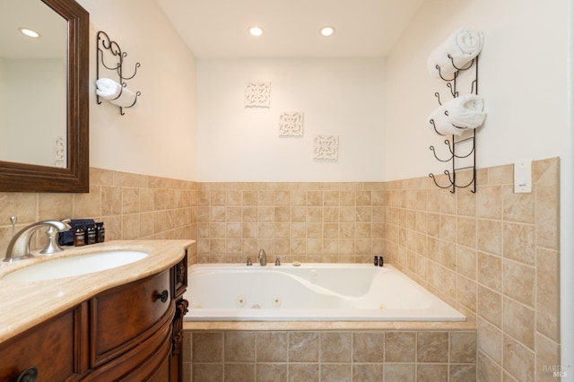 bathroom featuring vanity, recessed lighting, and a tub with jets