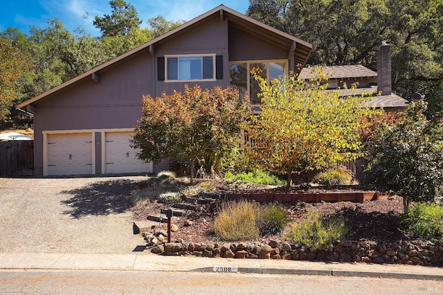 view of front of house with driveway, an attached garage, and fence