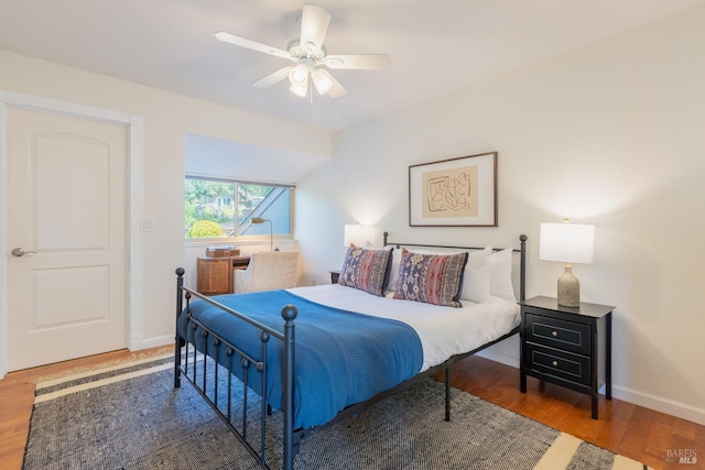 bedroom with a ceiling fan, wood finished floors, and baseboards