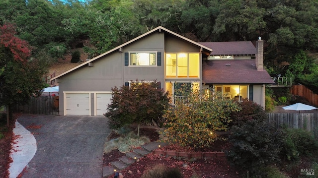 view of front of house featuring a chimney, concrete driveway, a garage, and fence