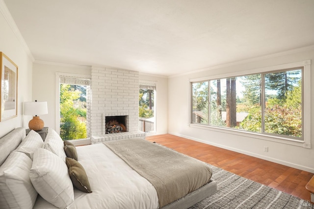 bedroom with light wood finished floors, a brick fireplace, baseboards, and ornamental molding