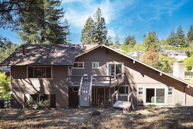 rear view of house with stairs, a deck, and a shingled roof