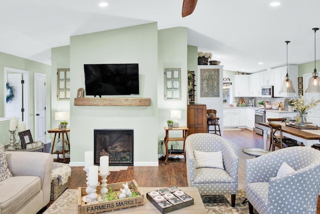 living area with recessed lighting, a fireplace, baseboards, and wood finished floors