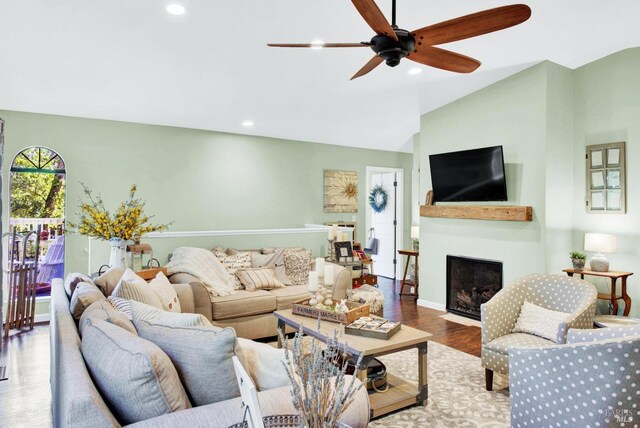 living room with wood finished floors, a fireplace with flush hearth, recessed lighting, ceiling fan, and vaulted ceiling