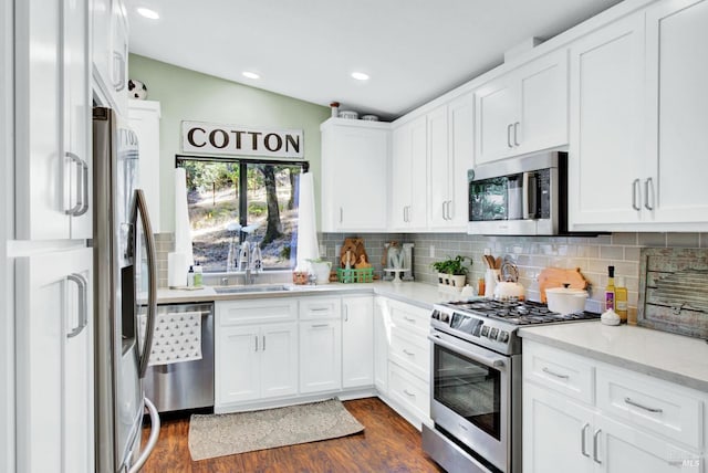 kitchen featuring dark wood-style flooring, a sink, white cabinets, appliances with stainless steel finishes, and backsplash