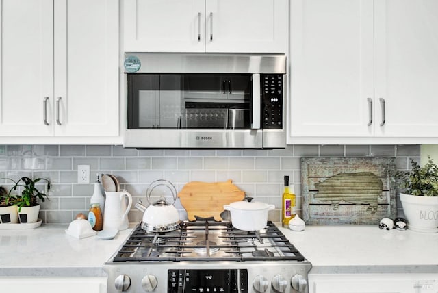 kitchen featuring white cabinets, light stone countertops, tasteful backsplash, and stainless steel appliances