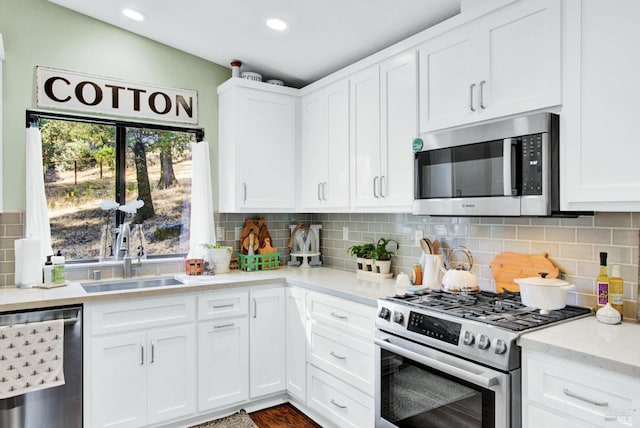 kitchen with recessed lighting, a sink, decorative backsplash, stainless steel appliances, and white cabinetry