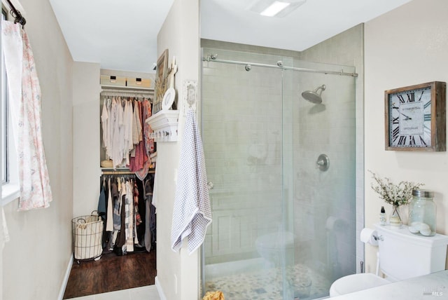 bathroom with a walk in closet, a shower stall, and toilet