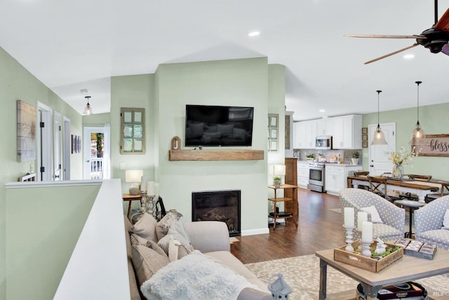 living room with a glass covered fireplace, recessed lighting, dark wood-type flooring, and ceiling fan