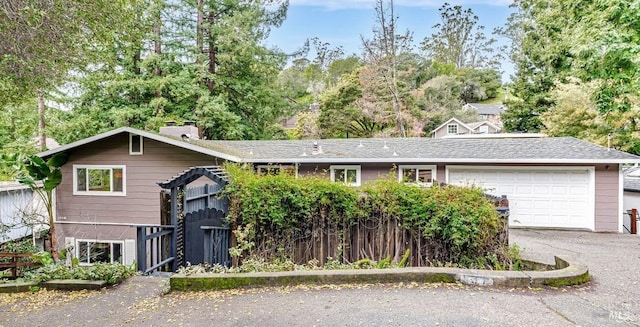 view of front of property featuring an attached garage, driveway, and fence