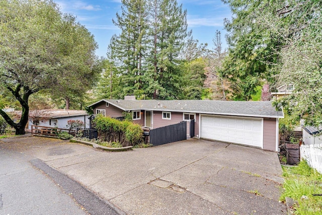 single story home with a chimney, concrete driveway, and fence