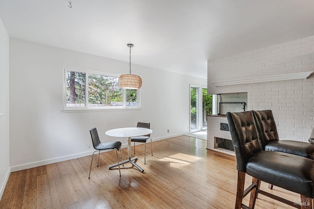 dining space with a fireplace, baseboards, and wood-type flooring