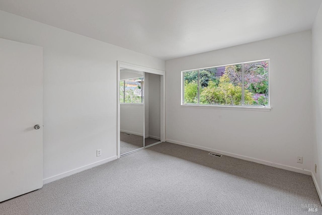 unfurnished bedroom featuring a closet, baseboards, visible vents, and carpet floors