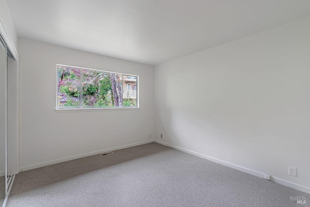 unfurnished room featuring visible vents, baseboards, and light carpet