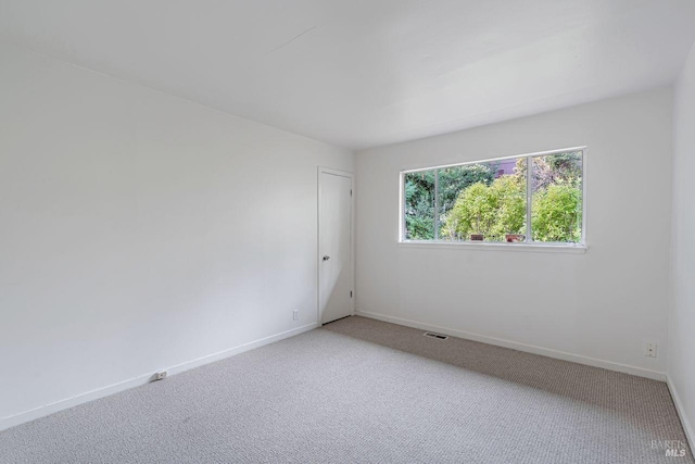 carpeted empty room with visible vents and baseboards