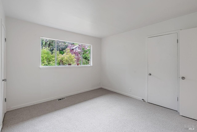 carpeted empty room featuring visible vents and baseboards