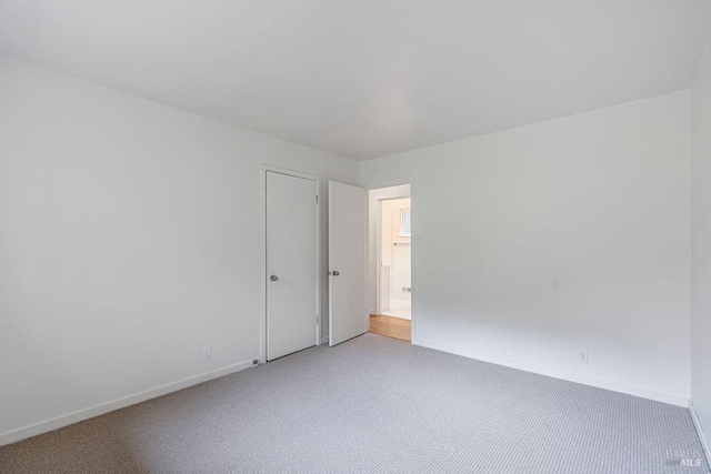 unfurnished room featuring carpet and baseboards