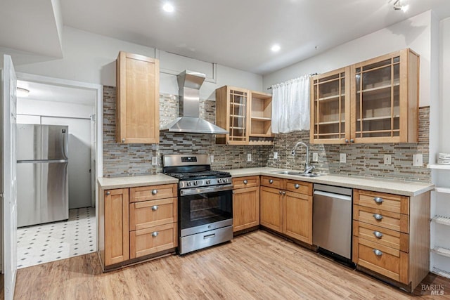 kitchen with light wood-type flooring, light countertops, stainless steel appliances, wall chimney exhaust hood, and a sink