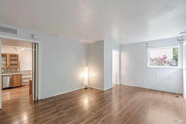 spare room with wood finished floors, visible vents, and baseboards