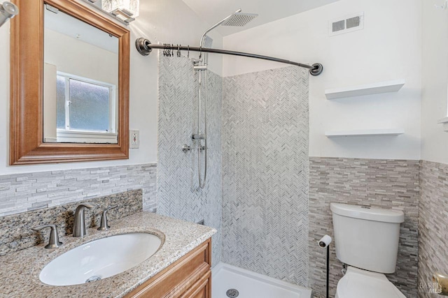 bathroom featuring visible vents, toilet, tile walls, and a tile shower