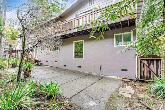 rear view of property featuring a patio, stucco siding, and crawl space