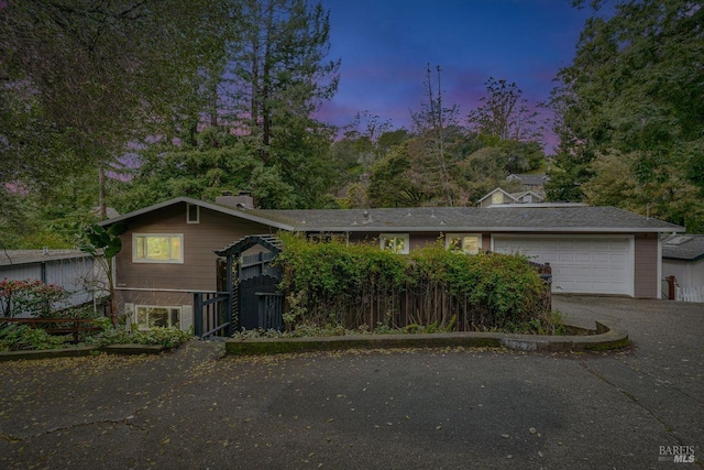 view of front of house with aphalt driveway, a garage, and fence