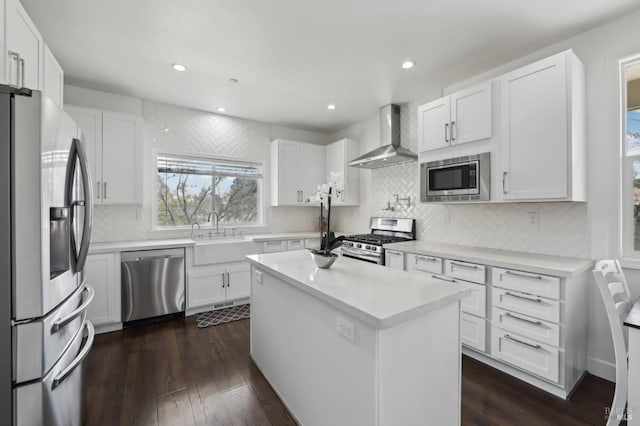 kitchen featuring dark wood-style floors, white cabinets, stainless steel appliances, wall chimney exhaust hood, and a sink