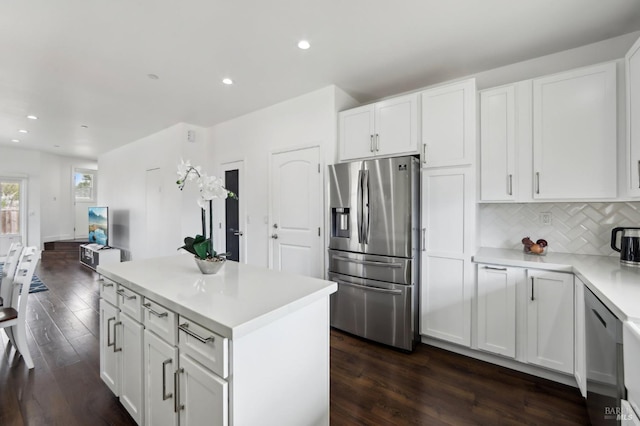 kitchen featuring tasteful backsplash, light countertops, white cabinets, stainless steel appliances, and dark wood-style flooring