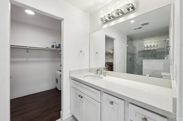 bathroom with visible vents, wood finished floors, a stall shower, and vanity