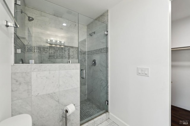 bathroom with a shower stall, toilet, and baseboards