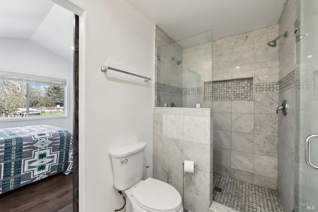 full bathroom featuring a tile shower, wood finished floors, toilet, and vaulted ceiling