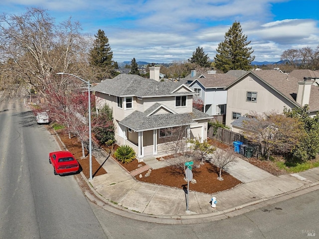 view of front of home featuring a chimney, a shingled roof, concrete driveway, a garage, and a residential view