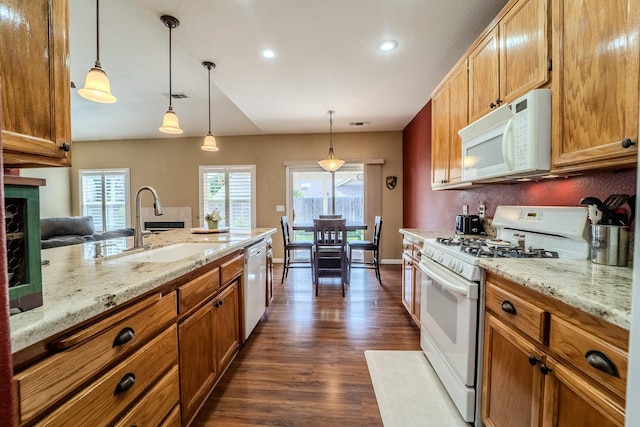 kitchen featuring visible vents, a sink, white appliances, brown cabinetry, and dark wood-style flooring