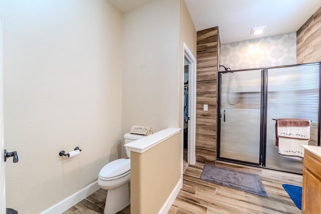 bathroom featuring a stall shower, toilet, vanity, and wood finished floors